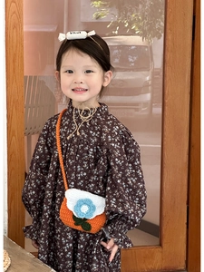 Close-up of a handmade crochet crossbody bag with orange body and white floral lid for kids