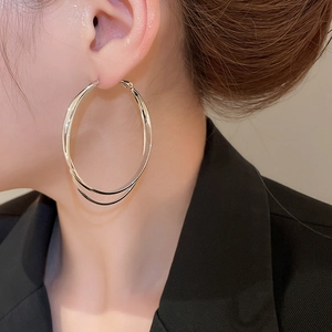 Gros plan de boucles d'oreilles doubles anneaux argentées portées par un modèle