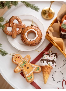 Close-up of gingerbread themed Christmas ornaments on a white tray with pine needles