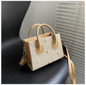 Detailed view of woven daisy crossbody bag with embroidery texture and yellow accents