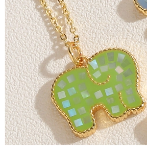 Macro detail of elephant pendant featuring green enamel inlay and 14K gold-plated shell textures