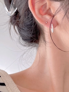 Close-up of minimalist silver hoop earrings featuring irregular textured metal on ear