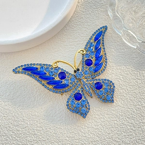 Elegant butterfly brooch with blue crystals and gold base on a textured background