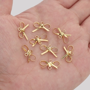 Close-up of 14K gold-plated bow charm connectors for DIY jewelry making in a hand