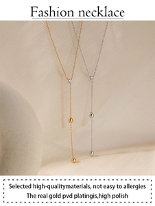 Detail of high-polish PVD gold Y-shaped necklace on minimalist aesthetic background