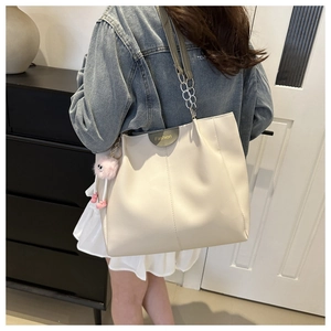 Dettaglio borsa tote bianco crema con ciondolo a pompon rosa ed etichetta alla moda