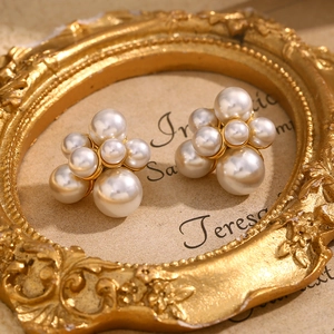 Detail shot of cluster pearl earrings in 18K gold plated steel on a vintage gold frame