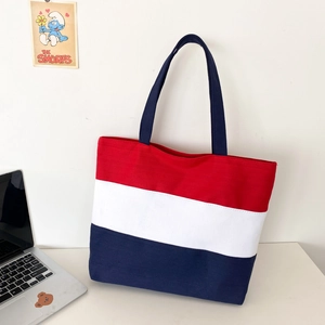 Three-color patchwork canvas tote bag displayed on a desk with a laptop and poster