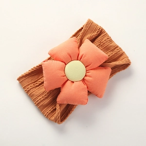 Detail of soft jacquard nylon baby headband with orange and yellow fabric flower accent