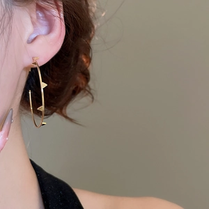 Detail of gold hoop earring with stud accents on female model side profile view