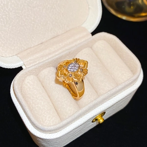 Close-up of a 24K gold-plated flower ring with micro-pave stones and adjustable band