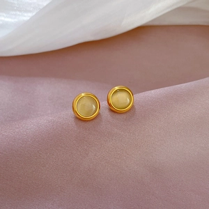 Macro shot of minimalist titanium gold stud earrings featuring yellow cat eye stones