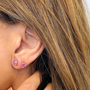 Macro close-up of pink heart-shaped zircon earrings with gold plating on a model