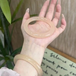 Detail view of semi-transparent geometric round bangles on a model's wrist with natural light