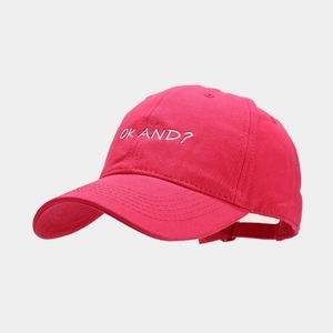 Detail of white OK AND? embroidery on magenta cotton canvas baseball cap surface