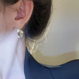 Close-up of a silver irregular geometric C-shaped earring worn by a model in a minimal style