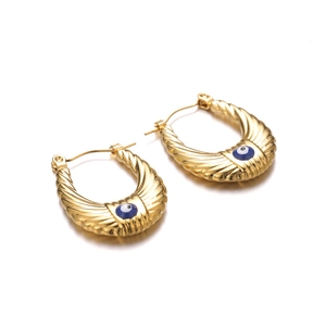 Golden U-shaped earrings with evil eye motif and textured wings on white background