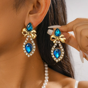 Close-up of vintage gold bow earrings featuring large blue water-drop crystals