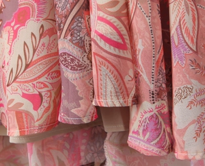 Close-up of lightweight paisley fabric with pink floral patterns and stitching detail