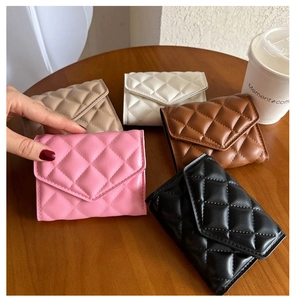 Close-up of quilted PU leather mini wallets in five colors on a wooden table