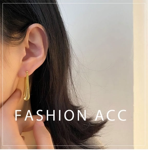 Close-up of golden teardrop pendant earring with brushed texture on model