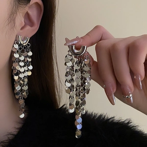 Boucles d'oreilles pendantes en métal argenté avec paillettes portées par un mannequin chic