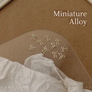 Detail showing 5x5.5mm gold mini bowknot alloy nail charms in a set of 20 pieces