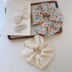 Floral scrunchies and lace hair clips set on a wooden tray for a fresh summer look