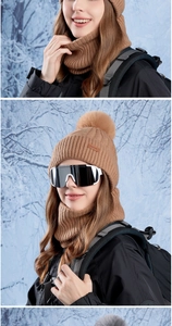 Detail of knitted winter beanie with pompom and matching neck warmer in outdoor snowy setting
