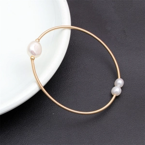 Macro shot of gold wire-wrapped bracelet featuring three elegant freshwater pearls