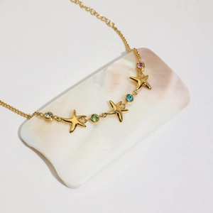 Detail of 18K gold starfish bracelet with multicolored zircons on pearl shell
