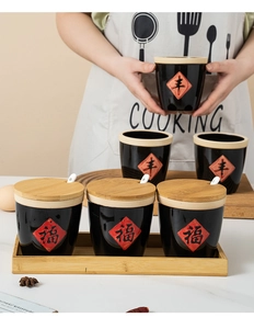Detail of hand-held black ceramic seasoning jar with bamboo lid and embossed character