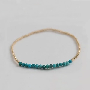 Macro detail of elastic beaded bracelet with gold round beads and turquoise stone accents