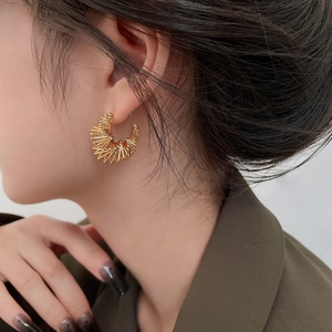 Detailed view of gold twisted spiral earrings on model showing modern metallic texture