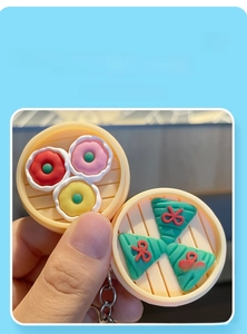 Détail d'un porte-clés cuiseur vapeur en PVC avec raviolis et brioches colorés