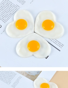 Detailed view of three heart-shaped fried egg PVC models on a lifestyle magazine background