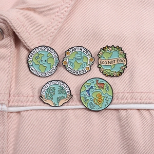 Close-up of five eco-themed enamel pins on a pink denim jacket showing detailed text