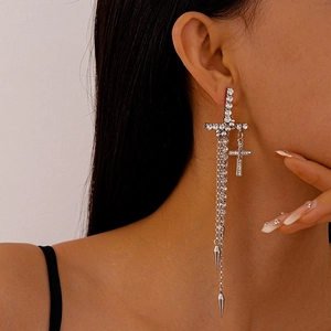 Close-up of silver cross earrings with sparkling rhinestones and long chain tassels