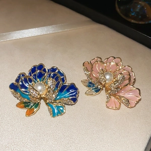 Close-up of enamel flower brooches with white pearls and sparkling crystal details