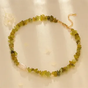Detail of green peridot gravel necklace with a white freshwater pearl on satin
