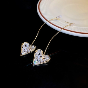 Boucles d'oreilles pendantes dorées avec cœurs en cristal sur une surface noire