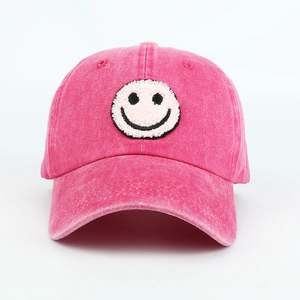 Detail of the white towel-embroidered smiley face on a rose pink washed cotton cap
