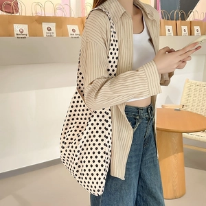 Detail shot of heavy canvas tote bag featuring large black polka dots on cream base