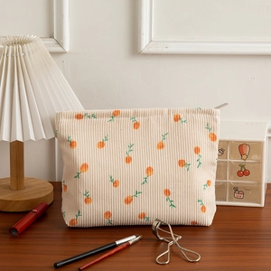 Detailed macro of floral corduroy makeup bag with orange prints and zipper closure