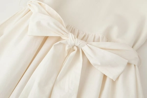 Detailed view of the elegant oversized bow knot on a cream-white knit waistline