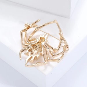 Detailed view of golden spider brooch back with secure pin clasp on white background