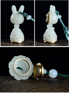Detail of white jade-like rabbit pendant with brass screw cap and cloud patterns