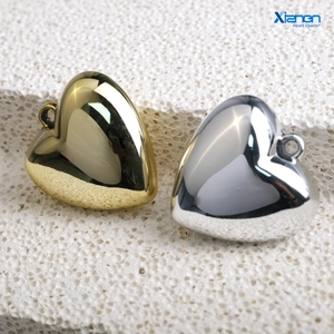 Macro shot of gold and silver heart pendants with mirror finish on white stone background