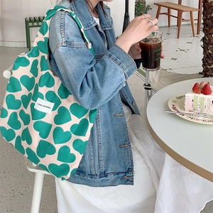 Corduroy heart pattern tote bag carried by a model in a bright outdoor cafe setting