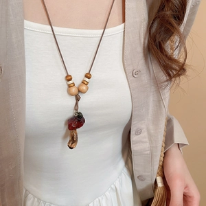 Macro detail of natural resin mushroom pendant with wood beads on brown cord